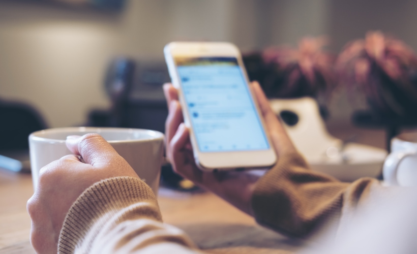 Man with coffee and cellphone open. Analysis performed by a social media agency.